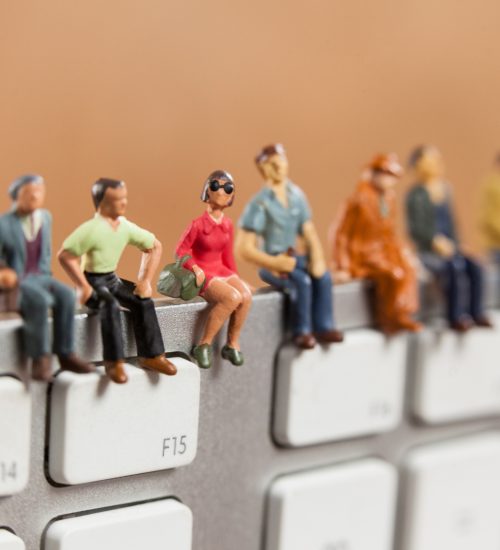 Conceptual image of miniature people sitting on top of keyboard