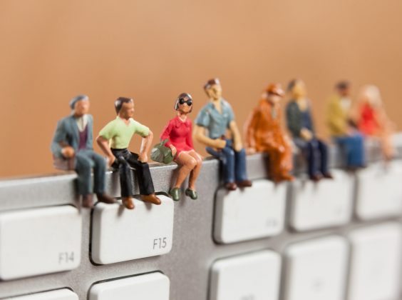 Conceptual image of miniature people sitting on top of keyboard